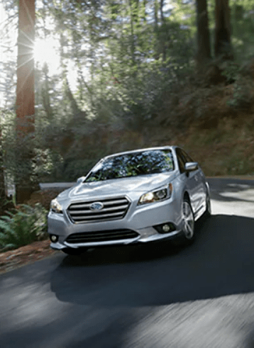 Subaru Legacy in silver driving in a moderate environment.